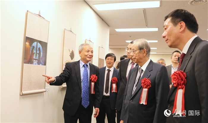 “湖州印象”攝影展主創(chuàng)、世界華人攝影協(xié)會(huì)副會(huì)長(zhǎng)馮學(xué)敏向吳江浩大使、福田康夫前首相等嘉賓介紹展出作品。（人民網(wǎng) 許可攝）