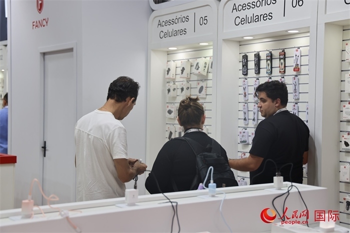 幾名參觀者在一個展臺前了解手機(jī)配件。（人民網(wǎng)記者 時元皓攝）