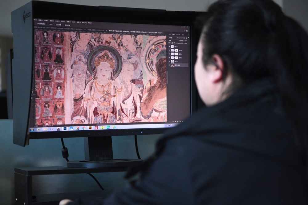 敦煌研究院文物數(shù)字化保護團隊圖像處理人員年海麗在拼接壁畫圖像（2023年4月25日攝）。數(shù)字化探索為莫高窟的保護與傳承開辟了全新路徑，數(shù)字技術讓敦煌文物走出洞窟，跨出國門，走向“永久保存、永續(xù)利用”。新華社記者 陳斌 攝