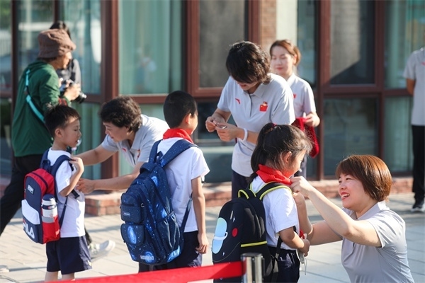 8月30日，雄安史家胡同小學學生體驗學校生活。老師為學生佩戴校徽。