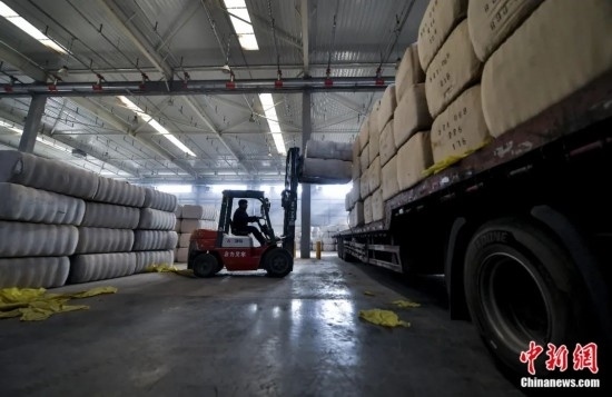新疆喀什綜合保稅區(qū)，喀什啟路國際貿(mào)易有限公司的倉庫內(nèi)，工人正在裝載從塔吉克斯坦和烏茲別克斯坦進(jìn)口的棉花。劉新攝