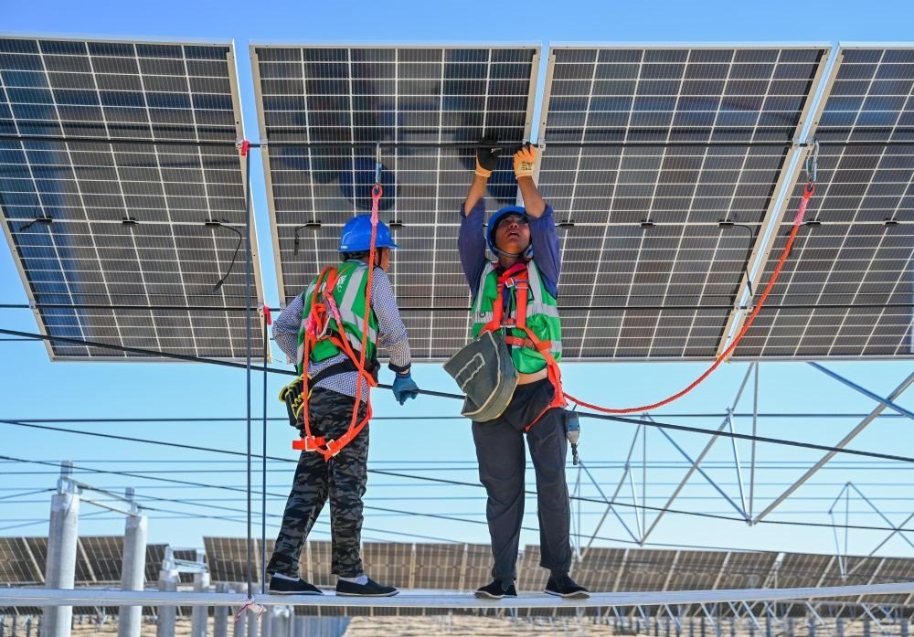 2023年7月22日，工人在位于內(nèi)蒙古杭錦旗庫(kù)布其沙漠億利生態(tài)示范區(qū)的蒙西基地庫(kù)布其200萬(wàn)千瓦光伏治沙項(xiàng)目工地安裝光伏板。新華社記者 劉磊 攝