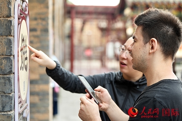 選手安德烈（俄羅斯）在老師指導(dǎo)下學(xué)習(xí)墻壁上張貼的生僻字。人民網(wǎng) 盧鵬宇攝