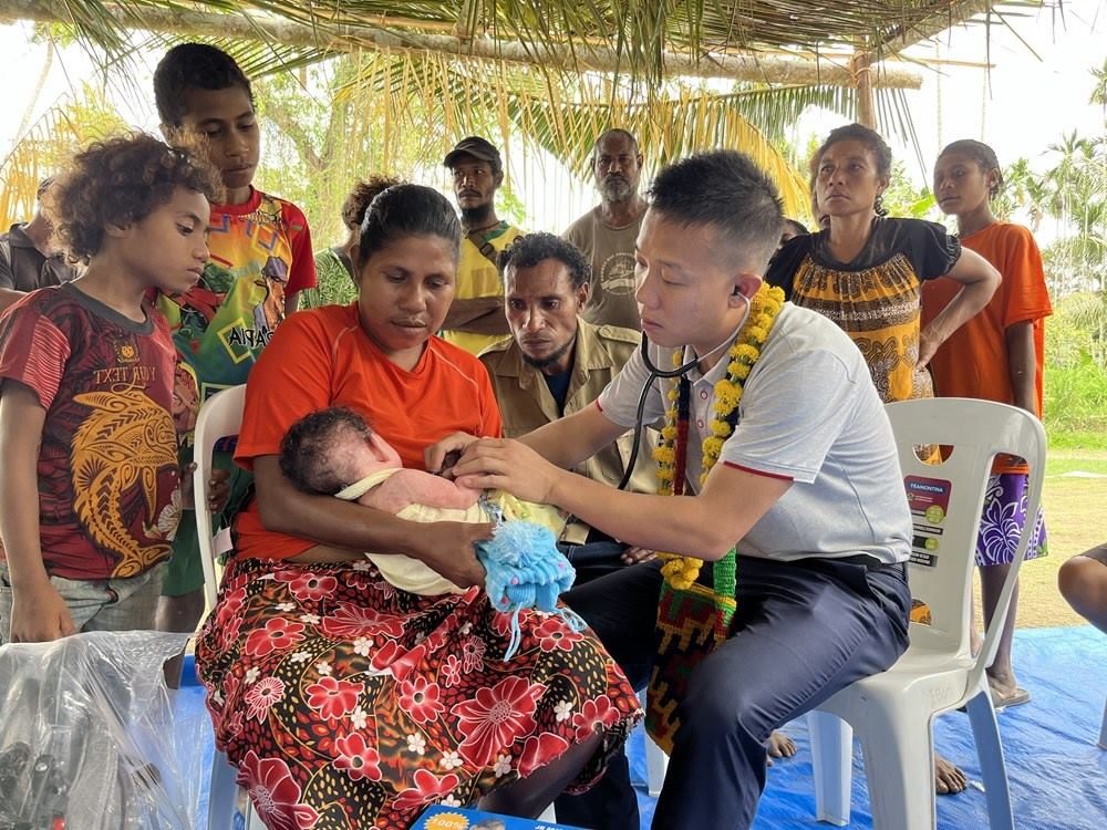 2023年8月5日，在巴布亞新幾內(nèi)亞中央省的一個(gè)村莊里，第12批援巴新中國(guó)醫(yī)療隊(duì)副隊(duì)長(zhǎng)、新生兒科副主任醫(yī)師劉振球?yàn)楫?dāng)?shù)貗雰郝?tīng)診檢查。新華社發(fā)（第12批援巴新中國(guó)醫(yī)療隊(duì)供圖）