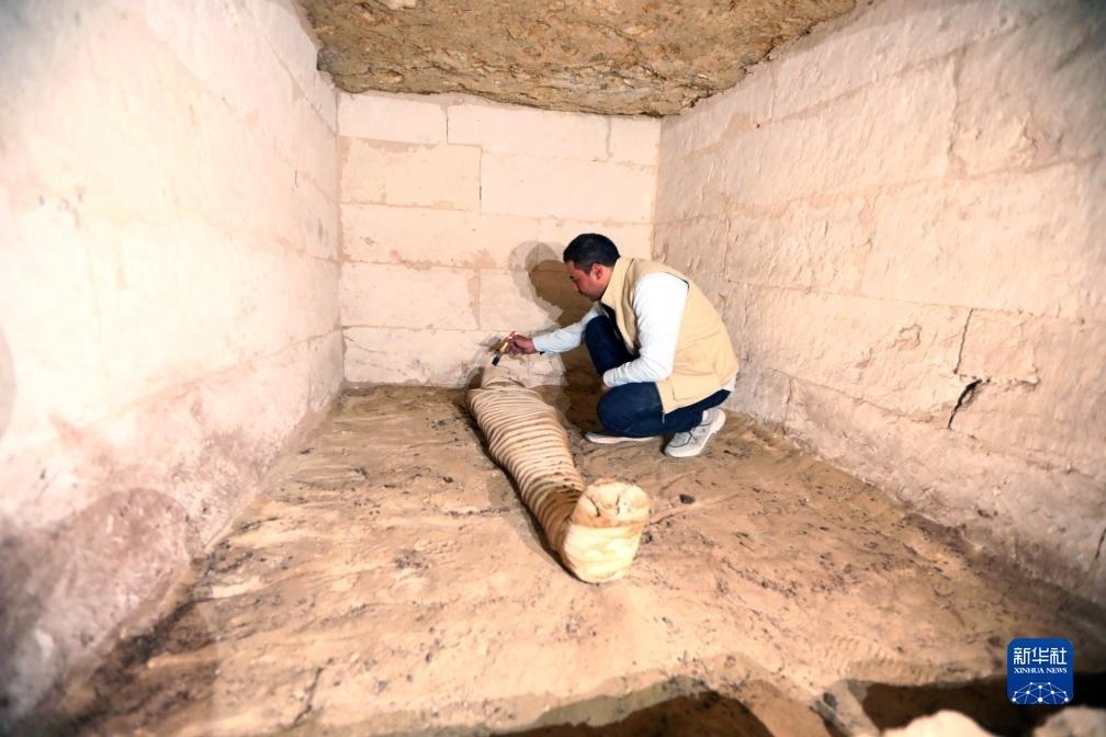 10月15日，在埃及明亞省考古現(xiàn)場，考古人員清理一座石鑿墓中的木乃伊。新華社發(fā)（艾哈邁德·戈馬攝）