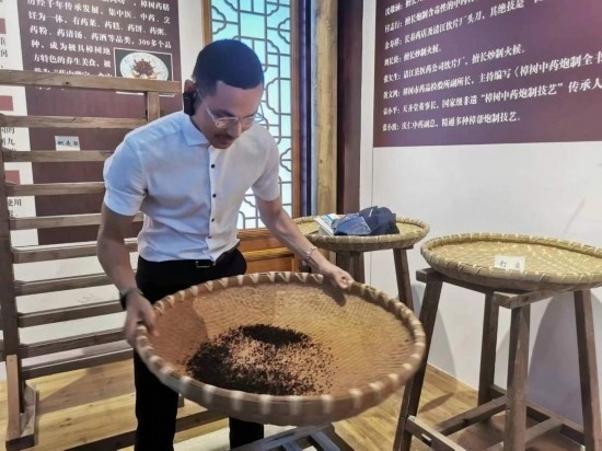 2023“一帶一路”媒體合作論壇聯合采訪團團員在非遺文化展示館體驗中藥炮制技藝。（本報記者 黃超攝）