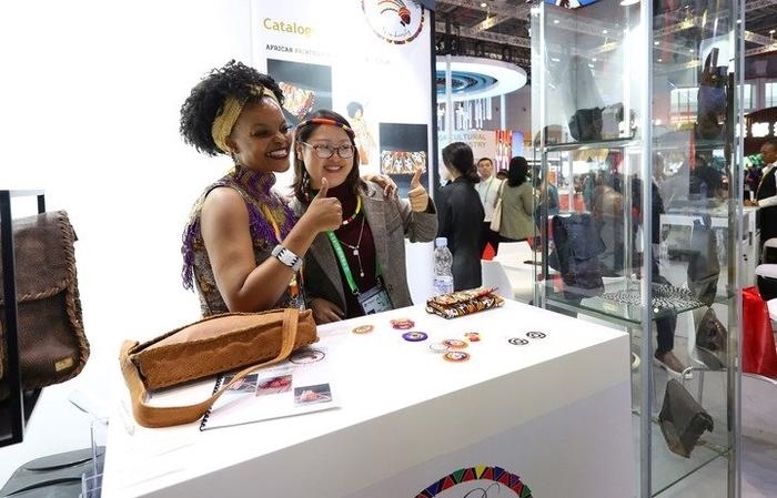 11月6日，一位參觀者（右）在第六屆進(jìn)博會國家展南非展臺試戴傳統(tǒng)首飾。