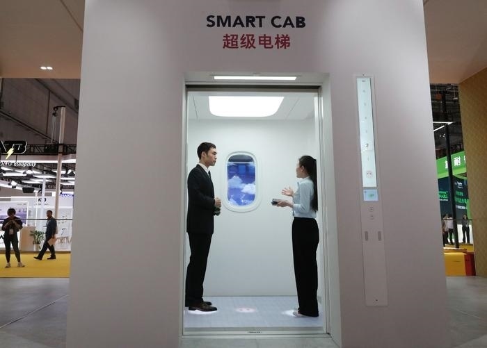 11月5日，工作人員（右）在第六屆進(jìn)博會上向參觀者介紹奧的斯公司全新推出的超級電梯。