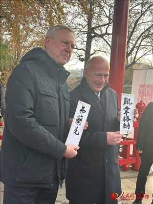 柏林市長韋格納（右）、動物園監(jiān)事會主席布魯克曼（左）手持中國文化中心工作人員現(xiàn)場手書的中文名字。人民網(wǎng)記者 徐馨攝