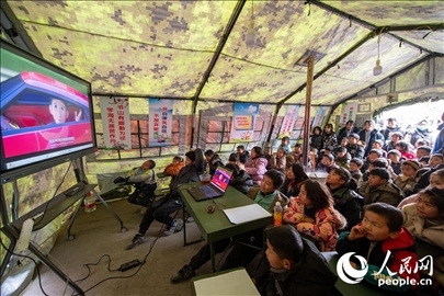 12月22日，在積石山縣大河家鎮(zhèn)大河村安置點，陸軍76集團軍某旅搭建的“臨時學(xué)校”內(nèi)，小朋友正在看動畫片。人民網(wǎng)記者 翁奇羽攝