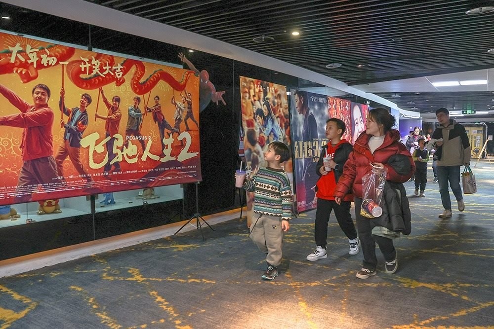△ 2024年2月16日，在江西贛州一家電影院，觀眾從春節(jié)檔電影的宣傳展板前走過。