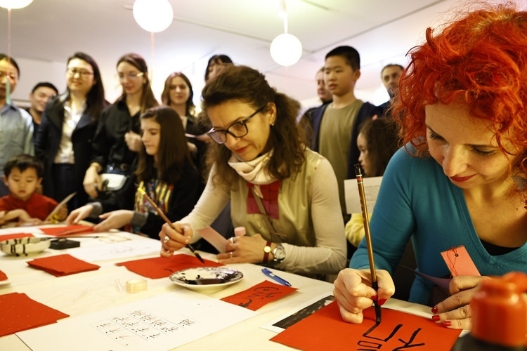 羅馬尼亞觀眾學(xué)習(xí)用毛筆寫“?！弊帧Ｖ袊?guó)文化中心供圖