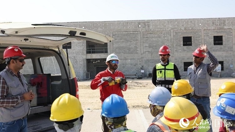 穆薩瓦爾(圖中紅衣人）現(xiàn)場(chǎng)演示工具操作規(guī)范。人民網(wǎng)記者 管克江攝