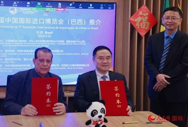 巴西外貿(mào)商會聯(lián)合會會長阿代爾·羅伯托（左）與中國國際進口博覽局副局長吳政平（中）現(xiàn)場簽訂協(xié)議。人民網(wǎng)記者 宋亦然攝