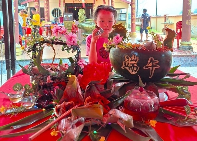 小朋友展示學(xué)裹粽子的成品照。組委會供圖