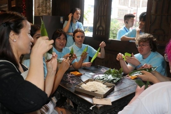 6月9日，美國青年代表在重慶永川松溉古鎮(zhèn)體驗(yàn)包粽子。新華社記者 周思宇 攝