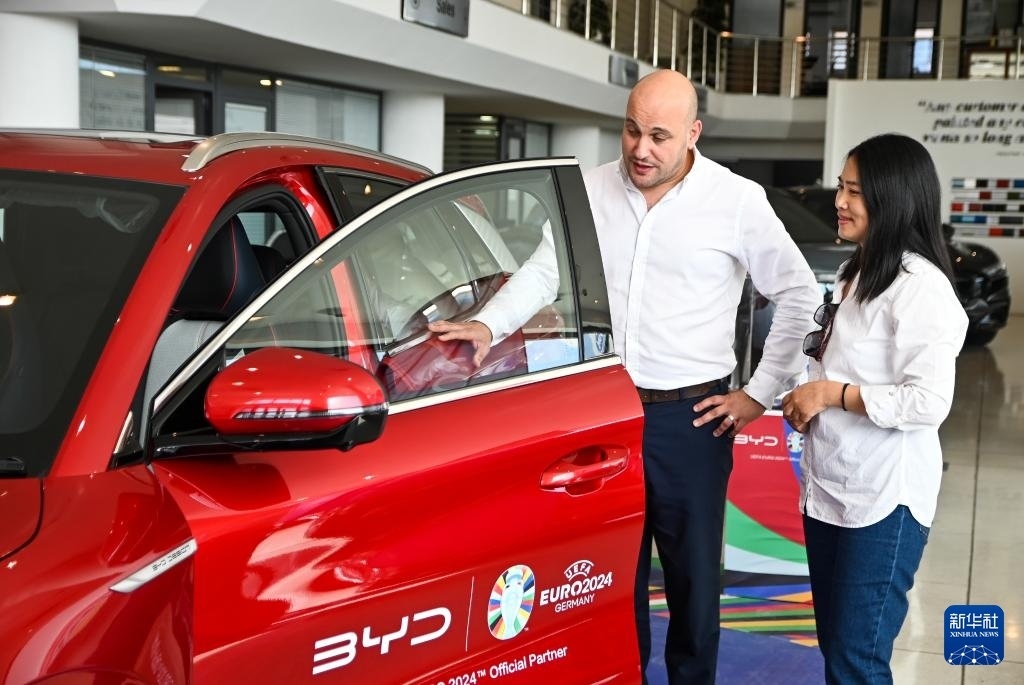 2024年5月29日，在馬耳他比爾基卡拉，馬耳他哈桑-扎米特汽車公司首席執(zhí)行官德古阿拉（左）介紹一輛比亞迪純電動汽車。新華社發(fā)（喬納森·博格 攝）
