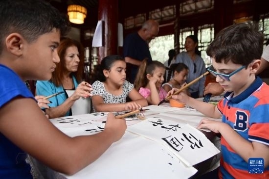 7月4日，在馬耳他桑塔露琪亞市的中國古典園林“靜園”，人們體驗(yàn)中國書法。新華社發(fā)（喬納森·博格 攝）