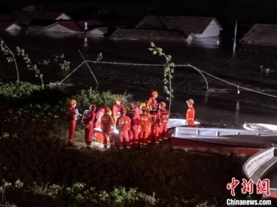  7月6日凌晨3時，在湖南岳陽華容縣團洲垸洞庭湖一線堤防，救援人員剛剛完成一次救援任務，遠處是被淹的民房。中新社記者 白祖偕 攝