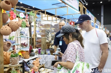 游客在蘭納博覽會特色展位上選購工藝品。人民網(wǎng)記者楊一攝