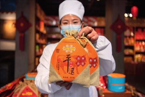 在位于山西省晉中市平遙縣的平遙古城南大街的一家平遙牛肉店內(nèi)，工作人員展示一款牛肉產(chǎn)品（資料照片）楊晨光攝 / 本刊