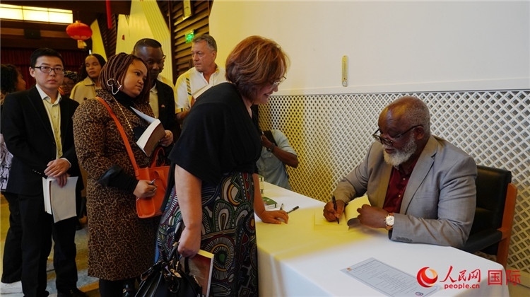 譚哲理在活動(dòng)現(xiàn)場(chǎng)簽名贈(zèng)書(shū)。人民網(wǎng) 劉暢攝