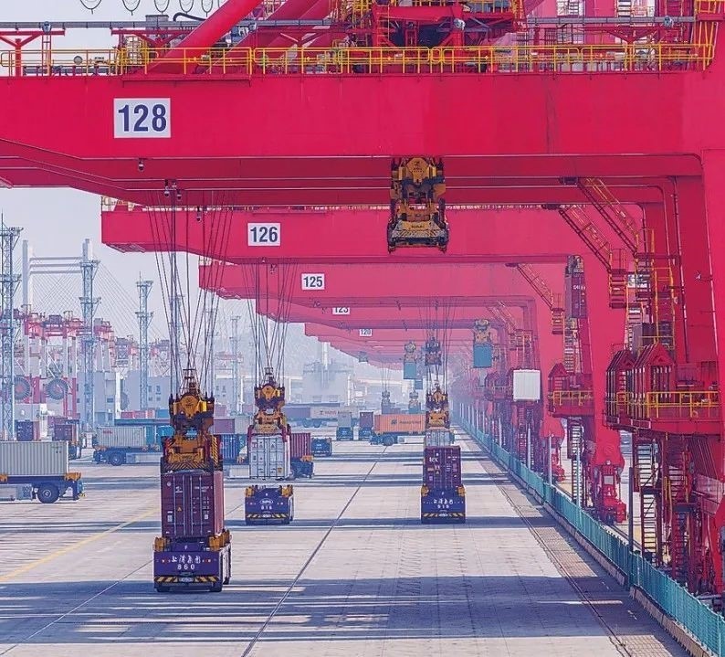 共建“一帶一路”國家在工作制度對接、技術(shù)標準協(xié)調(diào)、檢驗結(jié)果互認等方面強化合作、統(tǒng)一標準，貿(mào)易自由化便利化水平不斷提升。上海洋山港海關(guān)對接共建國家進出口貨物相關(guān)標準，推動通關(guān)一體化方式申報，提升通關(guān)效率。圖為無人駕駛的全自動導引車在洋山港穿梭往來，搬運集裝箱。王初 攝