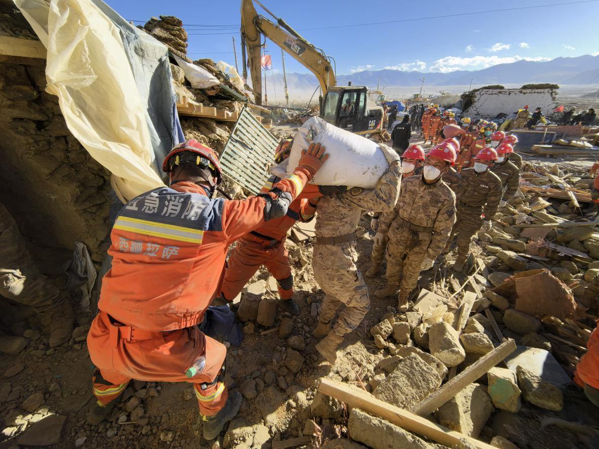 1月11日，定日縣長(zhǎng)所鄉(xiāng)古榮村，應(yīng)急消防等救援人員排隊(duì)接力搶運(yùn)掩埋在倒塌房屋下的群眾財(cái)物。人民日?qǐng)?bào)記者楊翹楚攝