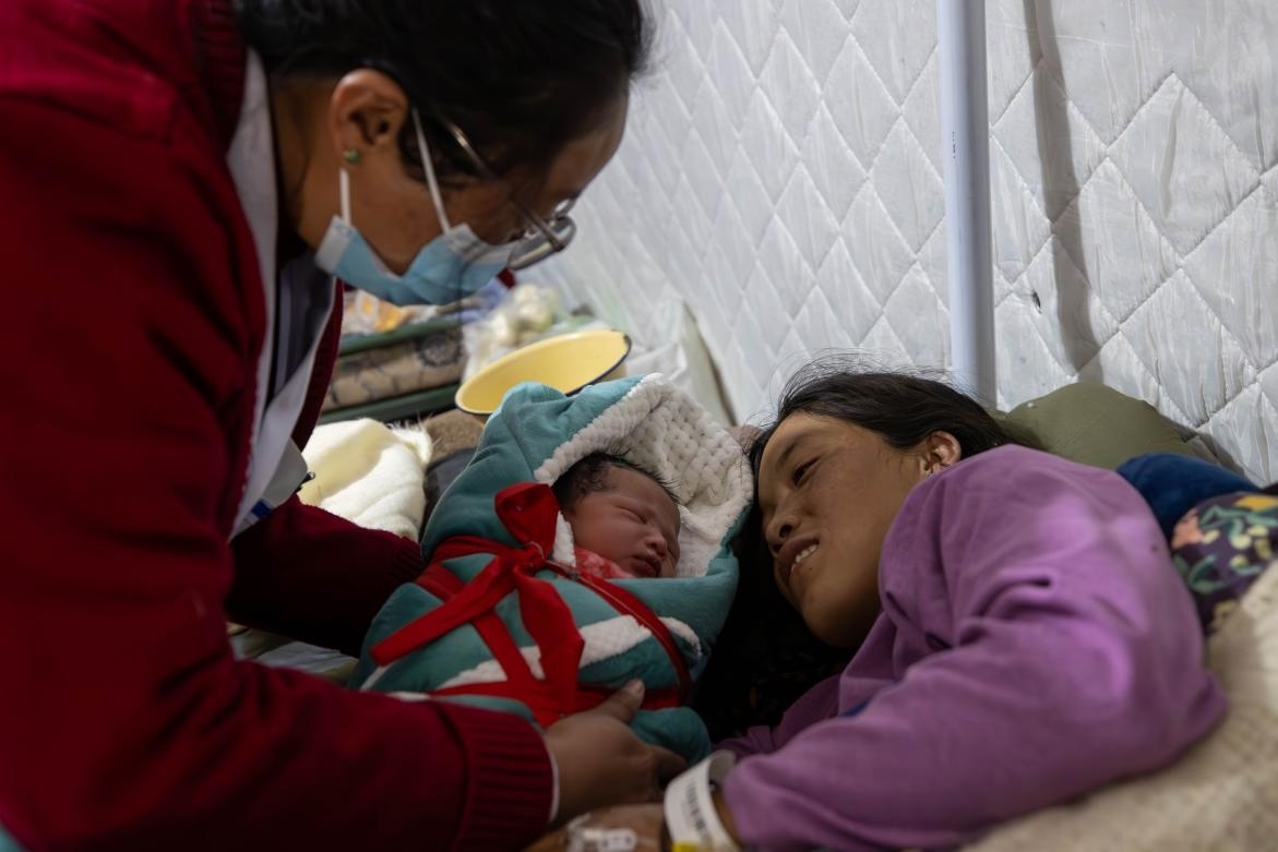 1月10日，定日縣中心醫(yī)院的婦產(chǎn)科醫(yī)生悉心照看一位母親和她懷里的新生兒。人民日?qǐng)?bào)記者張武軍攝