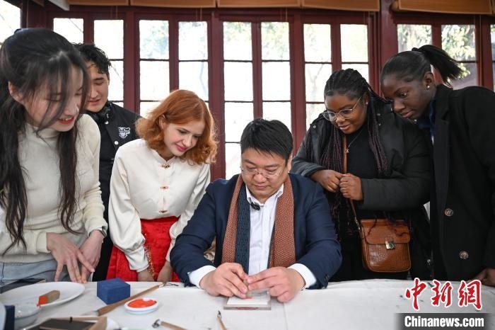 1月20日，篆刻家王臻向外籍留學生展示篆刻印章。當日，來自巴西、馬來西亞、加納、哈薩克斯坦的外籍留學生在浙江杭州西泠印社體驗福貼、春聯和篆刻，感受古老的中國傳統文化。中新社記者 王剛 攝