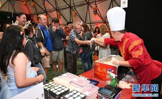圖為游客在燈節(jié)現(xiàn)場購買小吃。（圖片由奧克蘭中國文化中心提供）
