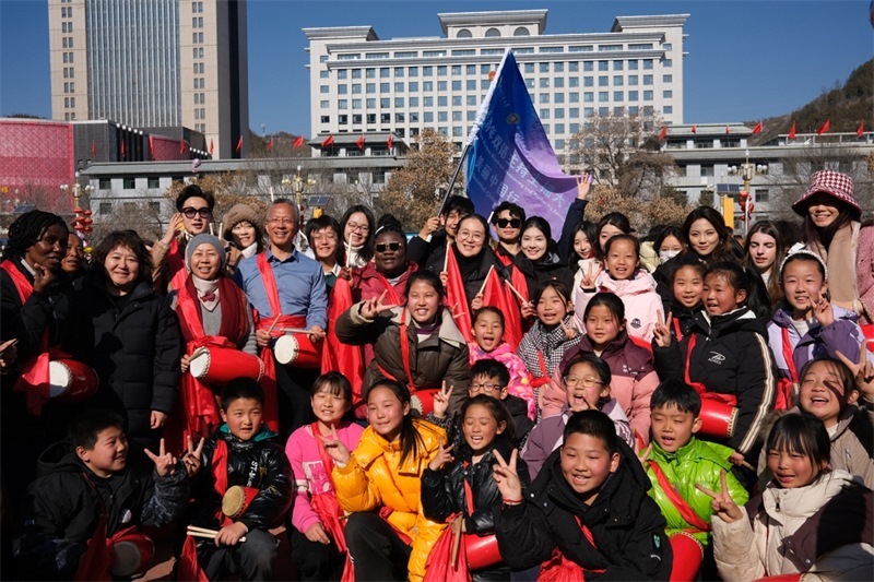 中外青年學(xué)子在安塞文化廣場觀看陜北腰鼓和大秧歌表演后合影留念，大家踏著鼓點(diǎn)共舞，翻飛的紅綢與躍動(dòng)的身影交織，在黃土地廣場上繪出一幅生動(dòng)的陜北民俗互動(dòng)畫卷