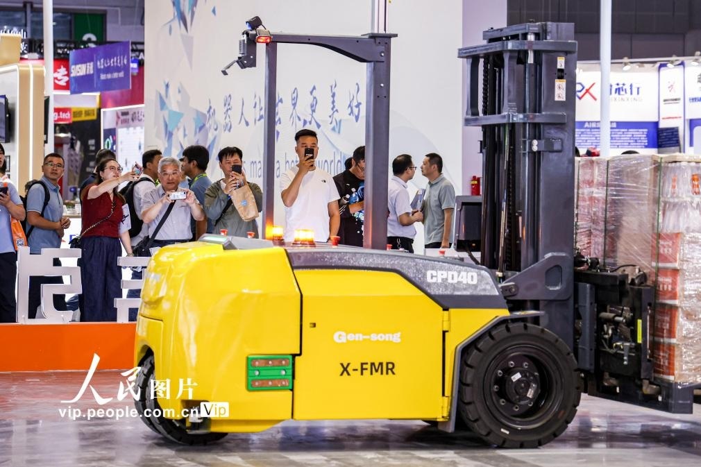 第24屆中國工博會現(xiàn)場，觀眾觀看叉取機器人作業(yè)演示。王初攝（人民圖片網(wǎng)）