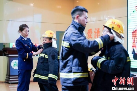 圖為學生們現場穿戴消防頭盔和戰(zhàn)斗服。中新社記者 趙宇航 攝