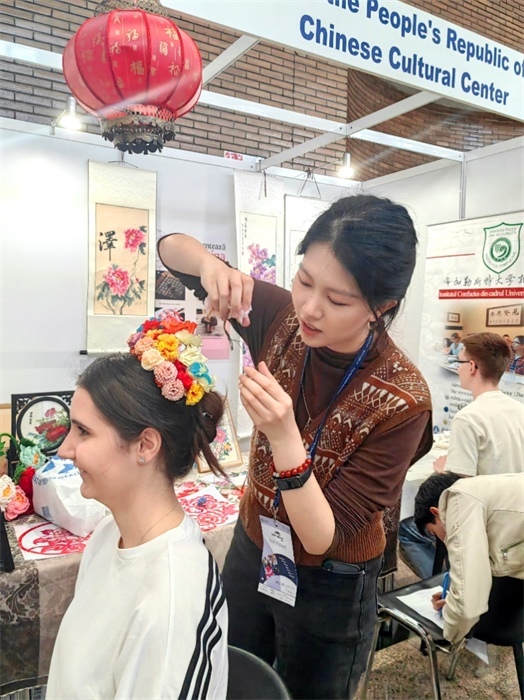 展覽正值羅馬尼亞迎春花節(jié)，國際中文教師志愿者潘婧穎向游客們介紹了國家非物質文化遺產(chǎn)——福建泉州的簪花文化。布加勒斯特大學孔子學院供圖。