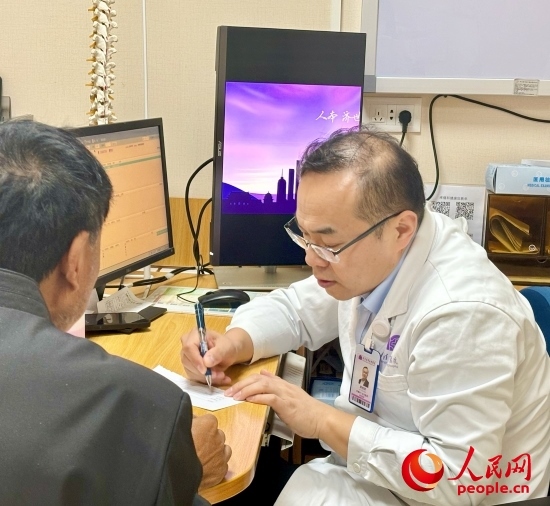 路桂軍接診時(shí)為患者寫下用藥提示。人民網(wǎng)記者 金慧慧攝