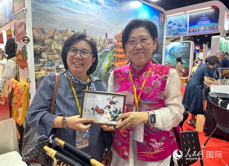 中國“大冶刺繡”傳承人劉小紅（右）參加泰國國際旅游展，向觀眾介紹中國非遺刺繡針法。人民網(wǎng)記者 簡承淵攝