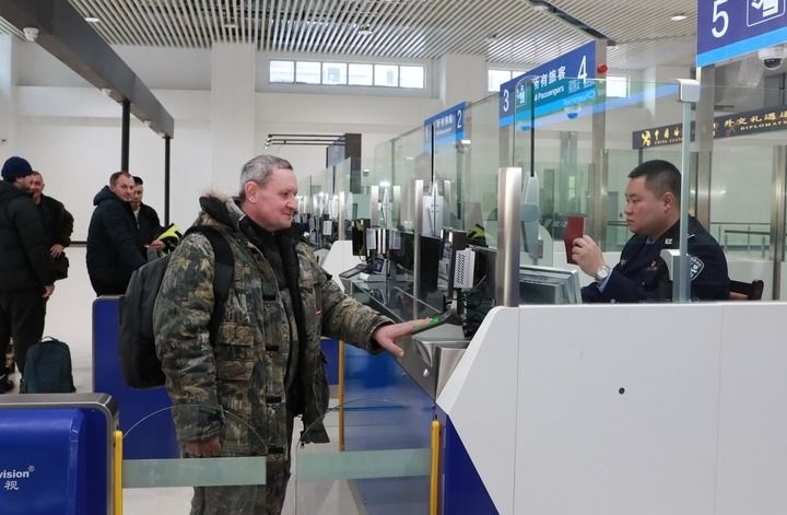 2024年12月10日，在黑河公路口岸旅檢大廳，黑河出入境邊防檢查站民警為首班次客車入境旅客辦理邊檢通關(guān)手續(xù)。當(dāng)日，中國(guó)黑河公路口岸—俄羅斯卡尼庫(kù)爾干公路口岸旅客運(yùn)輸正式開(kāi)通。新華社發(fā)（劉松攝）