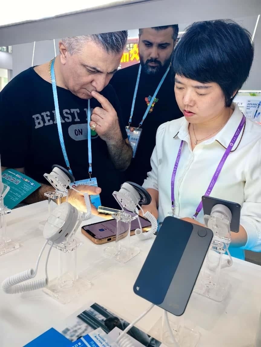 展臺(tái)工作人員向外商展示“AI TOP翻譯終端”。圖片來源：受訪者提供